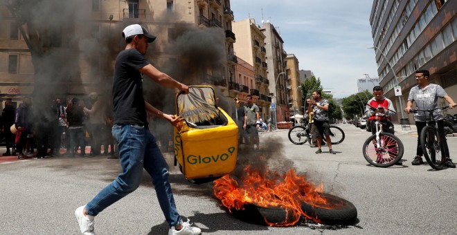 Un repartidor de Glovo quema una mochila durante una protesta tras la muerte de un compañero en Barcelona.-REUTERS/ALBERT GEA