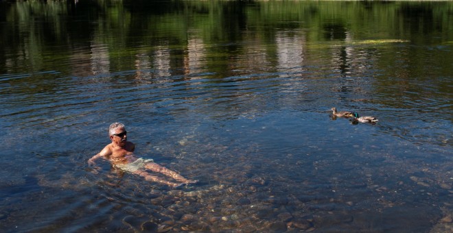 El sol y las altas temperaturas, entre 33 y 37 grados en la mayor parte de España, marcarán el inicio del mes de junio, con valores este viernes de 10 a 15 grados por encima de lo normal en el noroeste. En la imagen, un hombre se refresca en el río Miño.