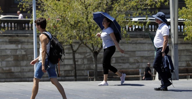 Una mujer se protege con un paraguas del calor en Bilbao, donde los valores registrados este viernes se sitúan entre 10 y 15 grados por encima de lo normal en el noroeste peninsular. | EFE