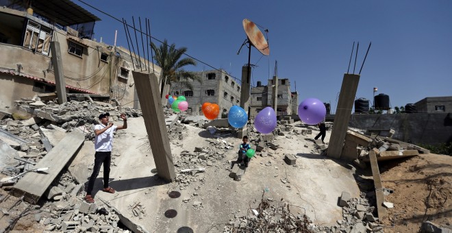 Un hombre palestino cuelga globos sobre las ruinas de una casa que fue destruida en los recientes ataques aéreos israelíes | Reuters