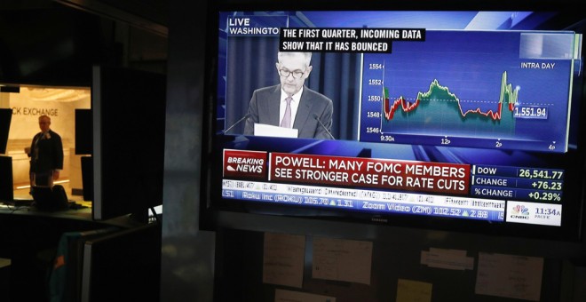 Un monitor de TV en el patio de negociación de la Bolsa de Nueva York en Wall Street muestra la rueda de prensa del presidente de la Reserva Federal, Jerome Powell, tras la reunión en la que se han mantenido sin tocar los tipos de interés. REUTERS/Lucas J