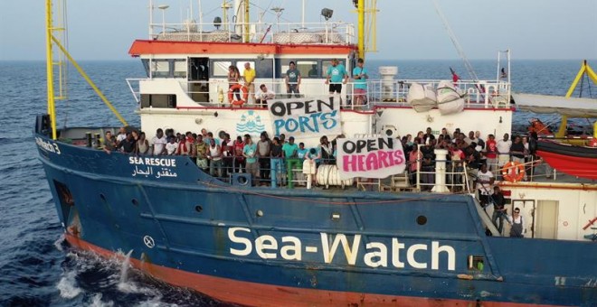 Migrantes esperan en la cubierta del barco de la ONG alemana Sea Watch, que continúa bloqueado este jueves ante las costas de la isla de Lampedusa. - EFE