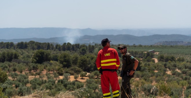 28/06/2019.- Un Agente Rural y un miembro de la Unidad Militar de Emergencias durante las tareas de extinción del fuego en la zona afectada por el incendio de la Ribera d'Ebre (Tarragona). / EFE - MARIO GASCÓN