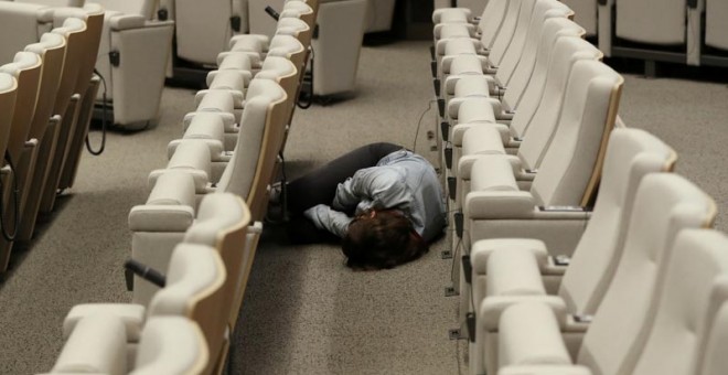 Una periodista duerme en el suelo de la sala de prensa de la sede de la Comisión Europea en Bruselas, mientras espera el final de la cumbre. (YVES HERMAN | REUTERS)