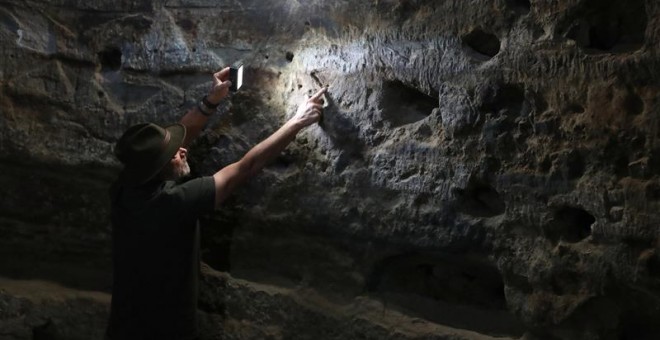 El arqueólogo Julio Cuenca, descubridor del yacimiento prehispánico de Risco Caído, en la cumbre de Gran Canaria, señala los grabados con forma de triángulo público que la luz del amanecer va recorriendo en el interior de la cueva desde el equinoccio de p