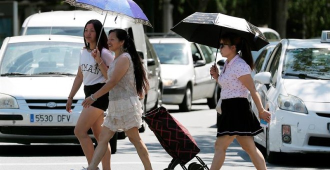 Tres mujeres se protegen del sol y del calor con sombrillas. /EFE