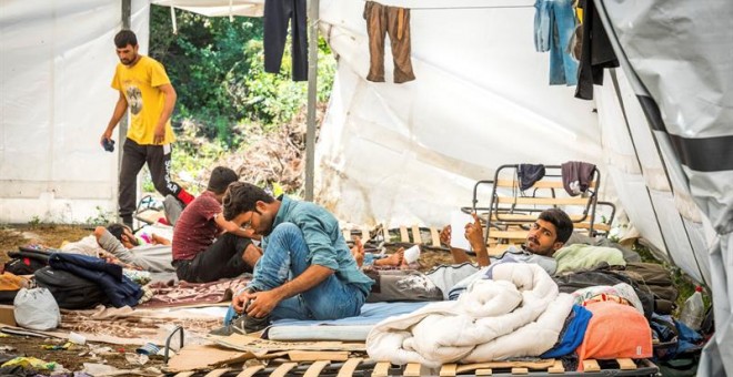 Refugiados del campo de acogida de Vucjak (Bosnia) descansan este jueves en el que fue un antiguo vertedero de basuras, situado en un bosque rodeado de campos de minas y sin agua corriente. EFE