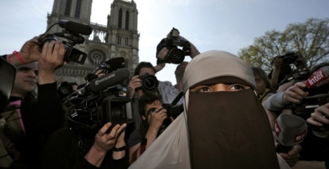 La primera mujer detenida en Francia por llevar burka, rodeada de periodistas. | Reuters