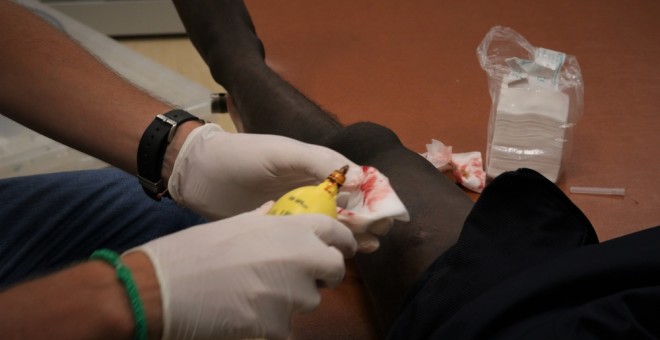 El médico de MSF Luca Pigozzi trata a una persona rescatada por el Ocean Viking por una infección en la parte superior de la pierna, causada por la exposición a condiciones insalubres durante un período prolongado de tiempo.- MSF