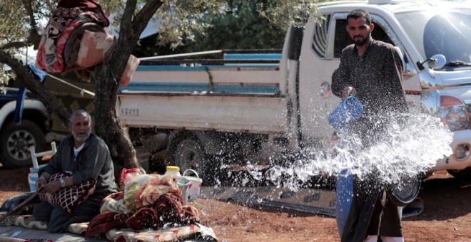 Un sirio desplazado vierte agua en un olivar en la ciudad de Atmeh, en la provincia siria de Idlib. REUTERS / Khalil Ashawi