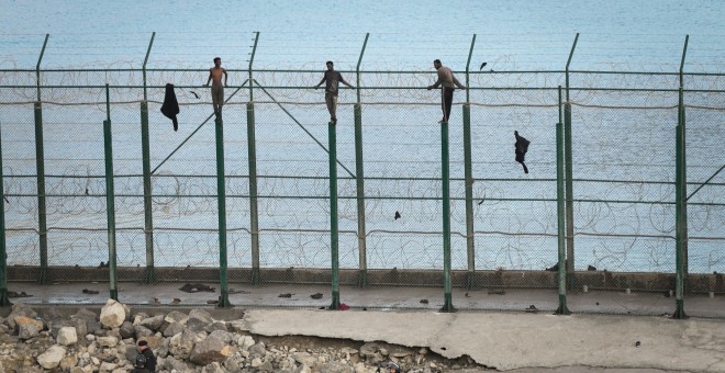 30/08/2019 - En la imagen, tres de un total de 153 migrantes, entran en Ceuta saltando su doble valla en la primera incursión en grupo en un año / EUROPA PRESS
