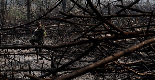 Un soldado camina por un tramo quemado del Amazonas en Rondônia. / RICARDO MORAES (REUTERS)