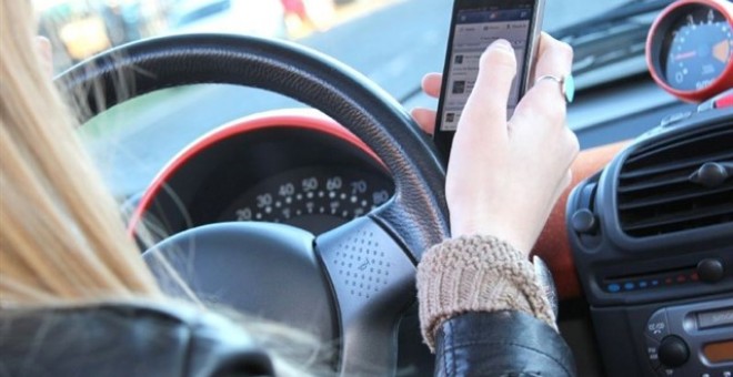 Una mujer usa el móvil al volante