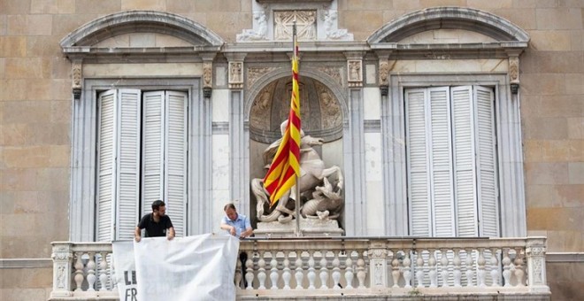 El moment en què personal de la Generalitat retira la pancarta amb el llaç groc. EUROPA PRESS / AVID ZORRAKINO