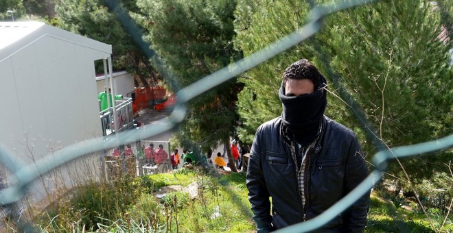 Un migrante tapa su rostro mientras aguarda en el Centro de Recepción de Inmigrantes de Lampedusa.- AFP