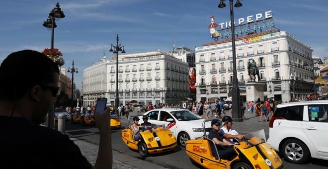 Un hombre toma fotos de turistas en una visita autoguiada de Gocar en la Plaza Puerta del Sol de Madrid. REUTERS/Susana Vera