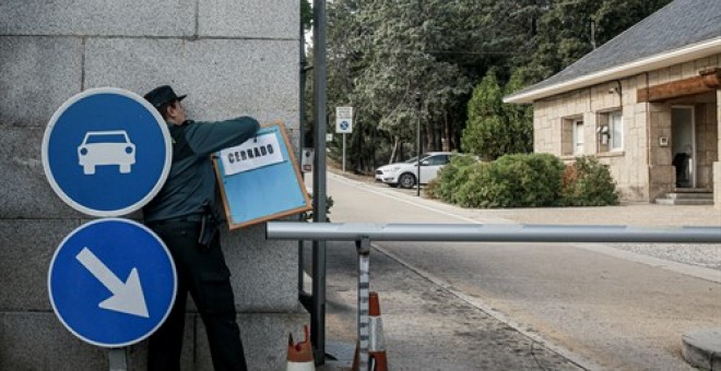 Una agente de la Guardia Civil coloca el cartel de cerrado en la valla de entrada de los coches al Valle de los Caídos