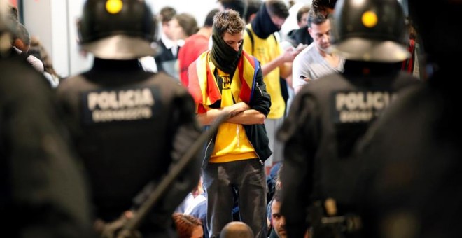 Agentes de los Mossos d'Esquadra controlan a los simpatizantes independentistas que han conseguido entrar en el T1 del Aeropuerto de El Prat tras el anuncio de la plataforma Tsunami Democràtic que ha llamado a paralizar la actividad del aeropuerto, en pr