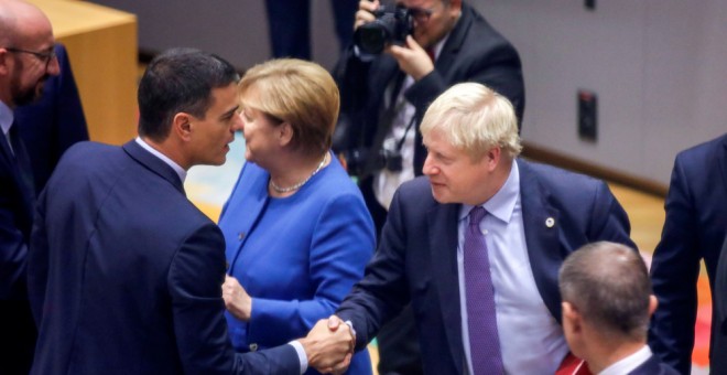 El presidente del Gobierno en funciones, Pedro Sánchez, saluda al primer ministro británico, Boris Johnson, en presencia de la canciller alemana Angela Merkel, al comienzo de la cumbre de la UE en Bruselas, en la que se ha dado el visto bueno al nuevo acu