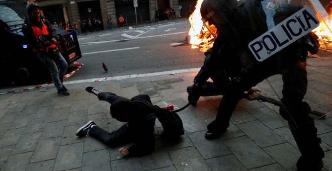 Un agente de la Policía Nacional golpe a un manifestante. / Reuters