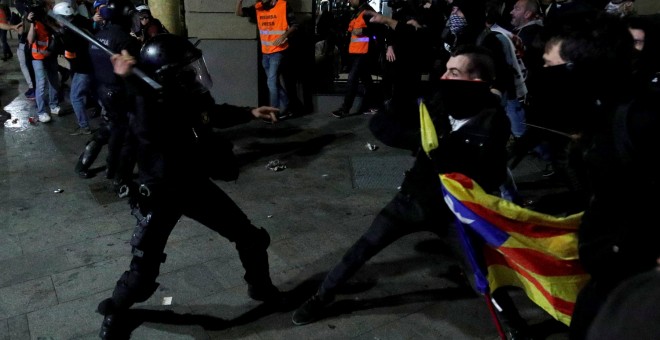 Un antidisturbios de los Mossos d/Equadra golpea con la porra a los manifestantes independentistas en Barcelona.- REUTERS/ALBERT GEA