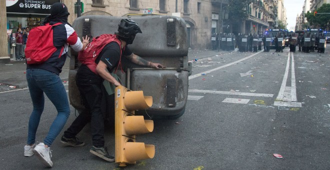 Dos encapuchados empiezan a montar una barricada, con un contenedor y un semáforo arrancado, en la Vía Layetana de Barcelona. GUILLEM SANS