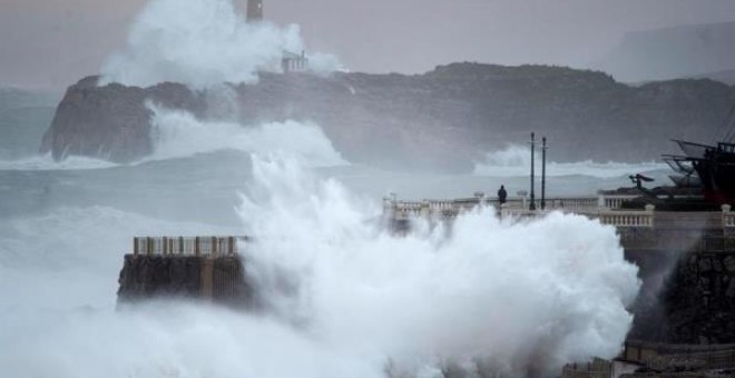 Una ola rompe en el faro de la isla de Mouro hoy domingo en la capital cántabra, en cuya comunidad.