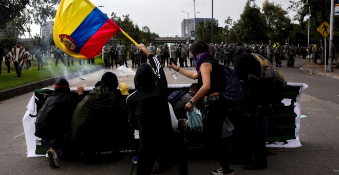 21/11/2019.- Un grupo de jóvenes se cubre frente a miembros de la Policía durante una manifestación en Bogotá (Colombia). / EFE - JUAN ZARAMA