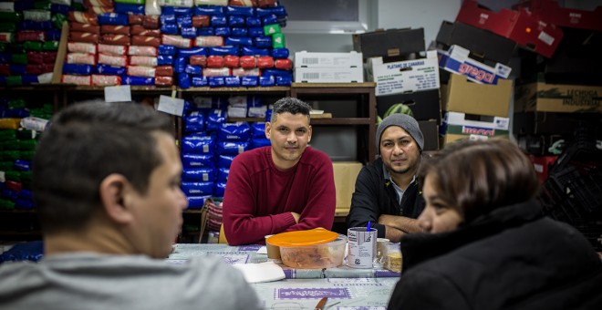 Jonatan Urdaneta y Alexander Orellana, solicitantes de asilo venezolano y salvadoreno, durante su comida de despedida con Mauricio Castaneda y Aida Burgo, procedentes de El Salvador, en el local de la Red Solidaria de Acogida en Puerta del Ángel, Madrid.