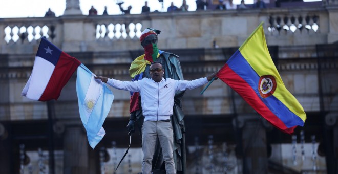 Un manifestante sostiene banderas nacionales colombianas, chilenas y argentinas durante una protesta mientras continúa una huelga nacional en Bogotá, Colombia, 4 de diciembre de 2019. REUTERS / Luisa Gonzalez
