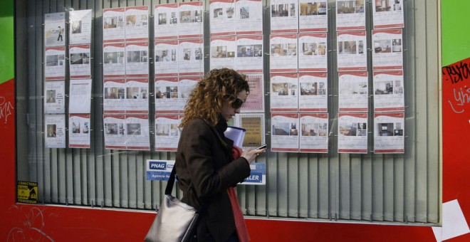 Una joven pasa por delante de una inmobiliaria con anuncios de casas en alquiler o en venta en el centro de Madrid. REUTERS/Andrea Comas