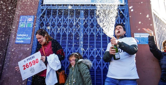 Laura Puentes, propietaria de la administración de lotería situada en la Rambla Guipúzcoa de Barcelona celebra con su marido y su hija las cinco series vendidas del número 26.590, agraciado con el Gordo de Navidad. /EFE