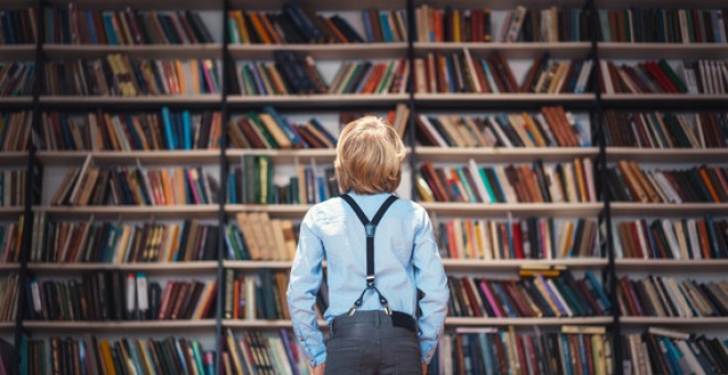 Imagen de archivo de un niño mientras observa una librería/ Adobestock