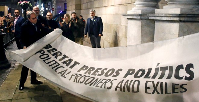 03/01/2020.- El presidente de la Generalitat Quim Torra (i) muestra la pancarta por la que la Junta Electoral Central le ha sancionado, ordenando que se le retire su credencial de diputado autonómico, lo que conlleva su inhabilitación. / EFE