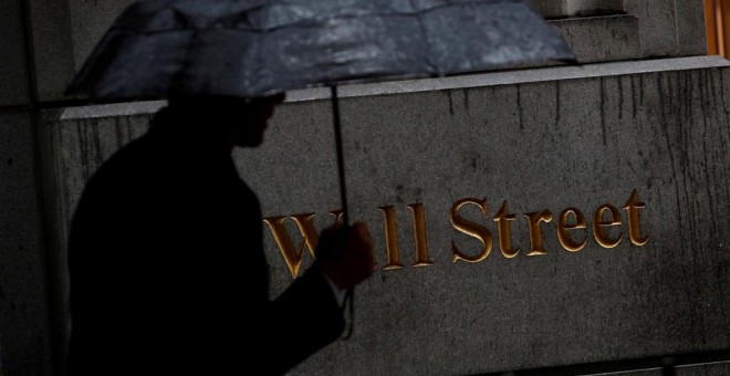 UIn hombre con paraguas pasa por delante de la sede del Bolsa de Nueva York (NYSE, según sus siglas en ingles), en  Wall Street. REUTERS/Brendan McDermid