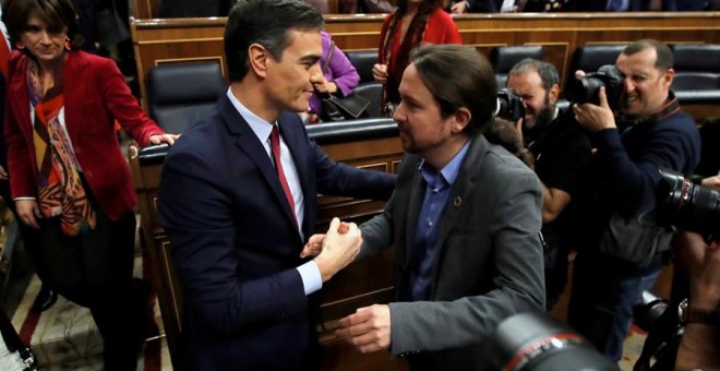 El líder de Unidas Podemos, Pablo Iglesias (d), felicita a Pedro Sánchez, quien logró este martes la confianza del Congreso para un nuevo mandato como presidente del Gobierno, al lograr una estrecha mayoría de 167 votos a favor, 165 en contra y 18 absten