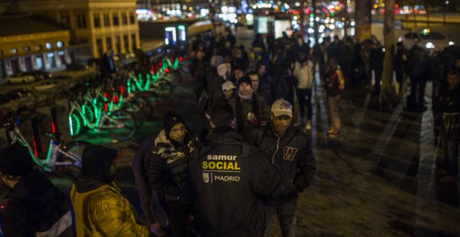 Solicitantes de asilo y personas sin hogar hacen cola para acceder a una de las camas de la campaña de frío del Ayuntamiento de Madrid.- JAIRO VARGAS