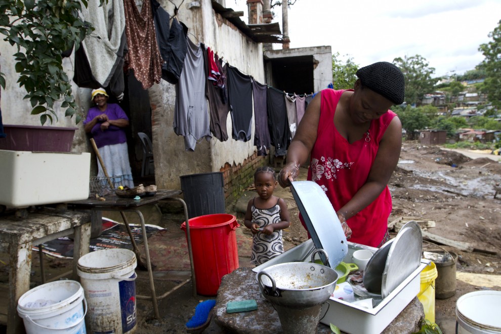 Una mujer lava los platos junto a su hijo en Durban. REUTERS