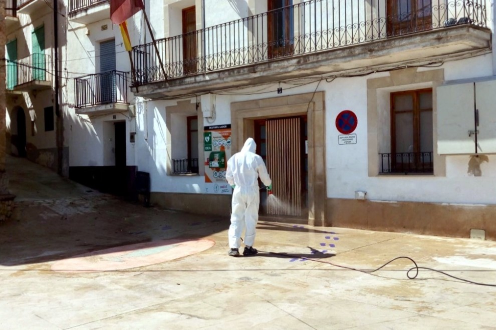 Pla general d'un operari de la Diputació de Tarragona desinfectant la plaça major de Paüls, a les portes de l'Ajuntament. ACN.