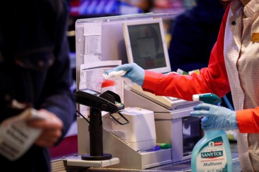 Una cajera desinfecta el datáfono en un supermercado. Foto: EFE/Archivo/Javier Etxezarreta