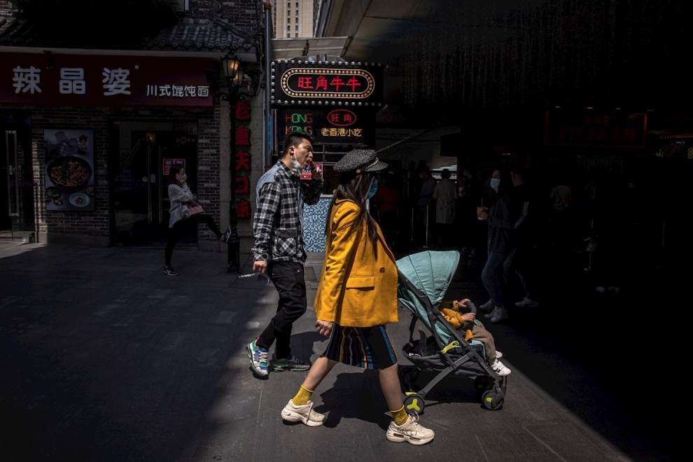 Las personas usan mascarillas mientras caminan en un área comercial en Wuhan, China, el 06 de abril de 2020. EFE / ROMAN PILIPEY