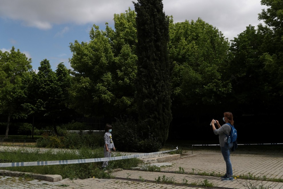 Una mujer realiza una foto a su hija en un parque clausurado de Madrid./ REUTERS