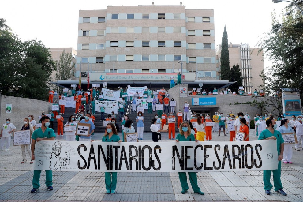Miembros del personal sanitario del Hospital Gregorio Marañón posan con una pancarta en la que se lee 'Sanitarios necesarios' durante una concentración este lunes en el exterior del hospital en Madrid, en la primera jornada de la Comunidad en la fase 1 de