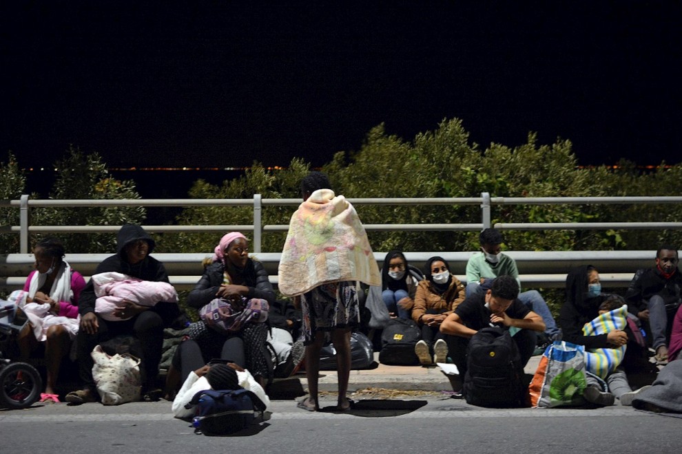 Un grupo de solicitantes de asilo descansa en la carretera, fuera ya del campo de refugiados de Moria, en la isla griega de Lesbos, incendiado esta madrugada.- EFE