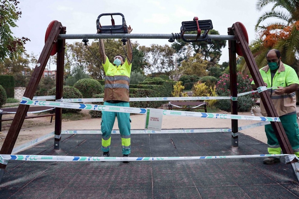 Varios operarios precintan unos columpios en un parque de Valencia este viernes | EFE