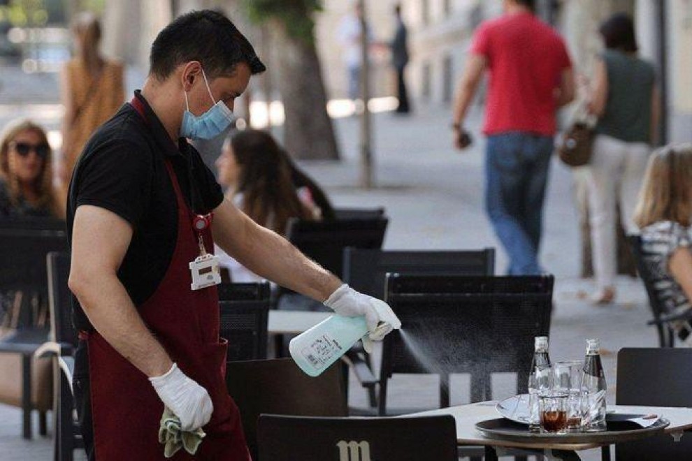 Un camarero desinfecta una mesa de una terraza / EFE