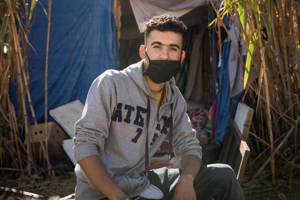 Ahmed vive en una chabola con tres colchones, construida entre cañas junto al cauce seco y lleno de basura que pasa al lado del CETI de Melilla.- EFE/Jesús Blasco de Avellaneda