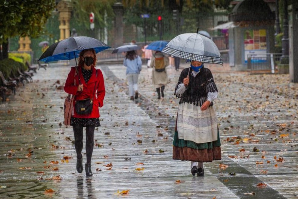 Dos mujeres pasean bajo la lluvia en el paseo de Los Álamos, en el centro de Oviedo, Asturias. EFE/Alberto Morante