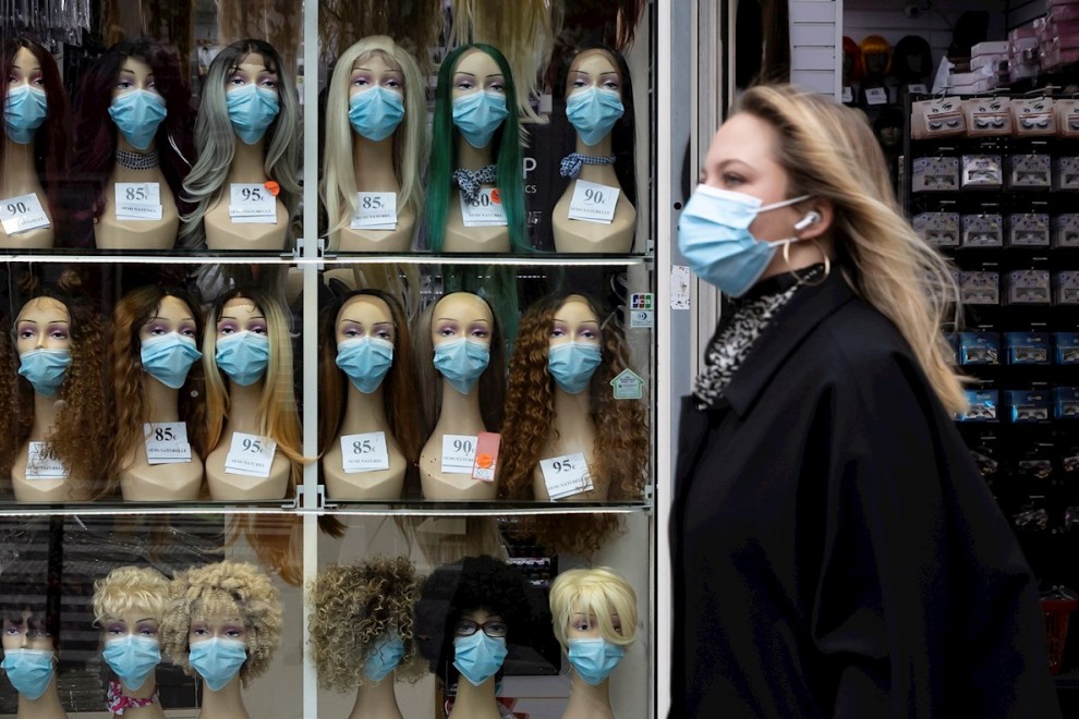 Una mujer ataviada con máscara sanitaria pasa frente a un escaparate este miércoles en París. EFE