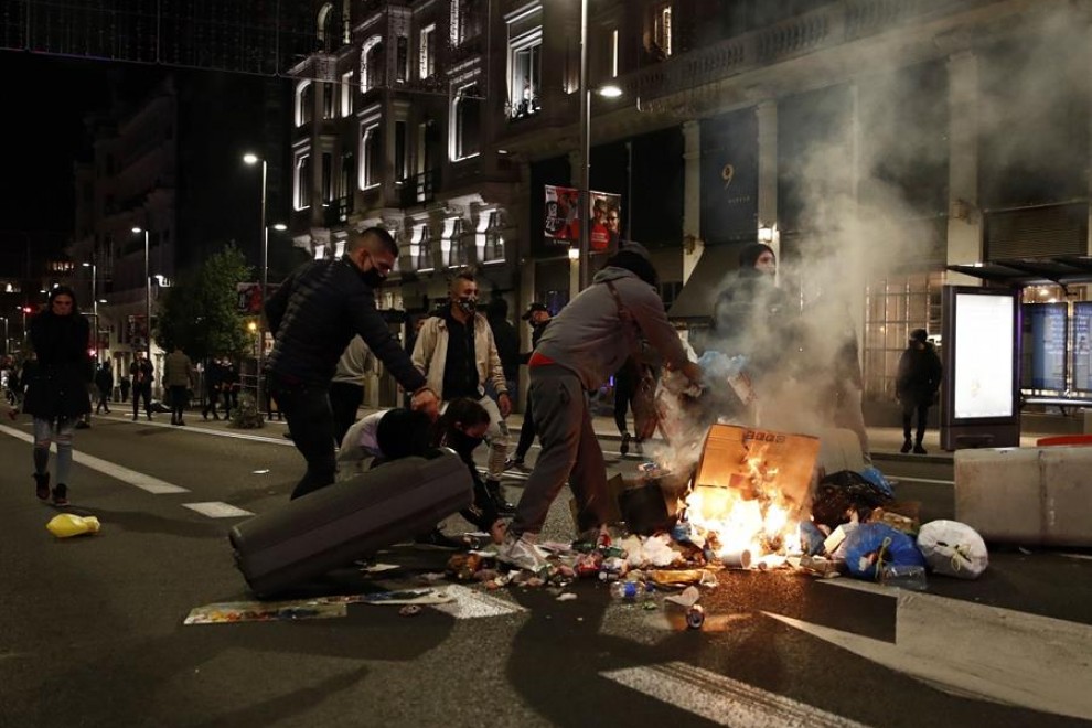 Varios participantes en las protestas convocadas esta noche incendian cubos de basura en la Gran Via de Madrid, por las medidas tomadas tras el aumento de contagios por coronavirus.